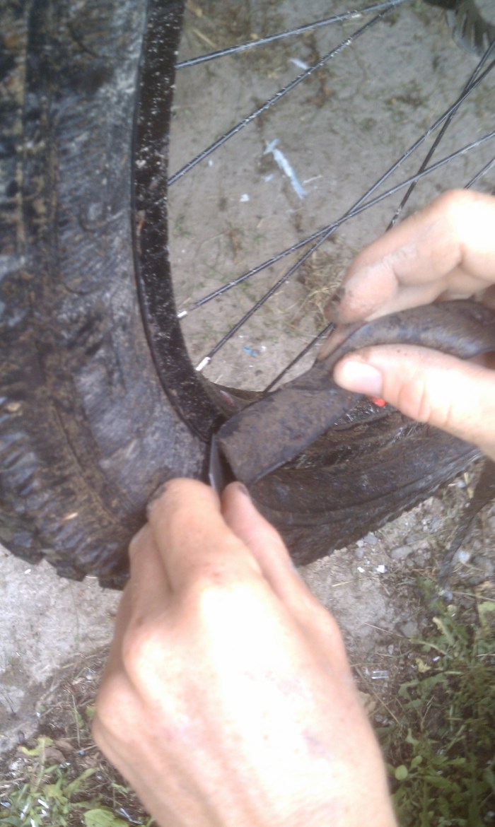 Pull the tube and let the tire turn and the tube will pull into the blade. Don't cut the tire, position the blade so if the tire moves the tip will hit the rim instead.